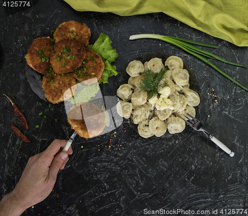 Image of Fried cutlets and russian pelmeni on black background