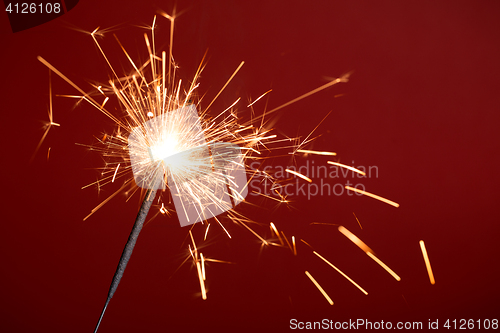 Image of Burning sparkler on red background