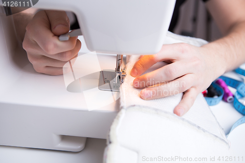 Image of Young girl stitching white cloth