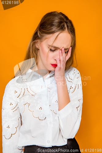 Image of The serious frustrated young beautiful business woman on orange background