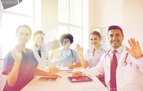 Image of happy doctors meeting and waving hands at hospital