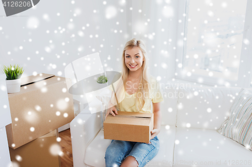 Image of smiling young woman with cardboard box at home