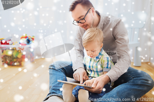 Image of father and son with tablet pc playing at home