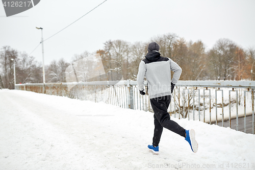 Image of man running along snow covered winter bridge road