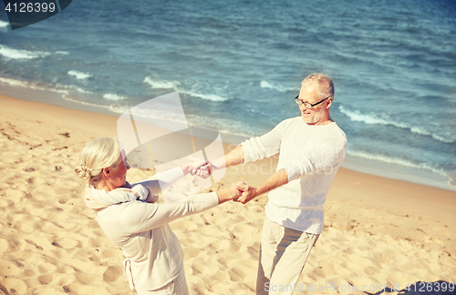 Image of happy senior couple holding hands on summer beach