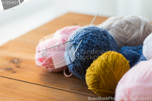 Image of knitting needles and balls of yarn on wood