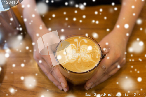 Image of close up of hands with latte art in coffee cup