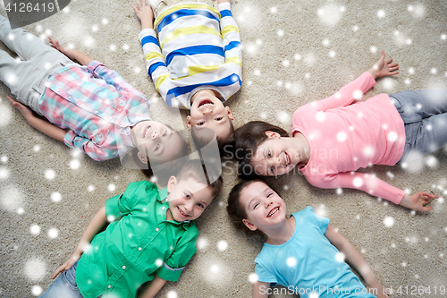 Image of happy smiling children lying on floor over snow