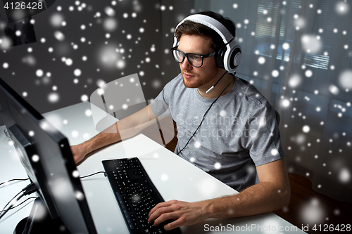 Image of man in headset playing computer video game at home