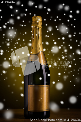 Image of bottle of champagne with golden label over snow