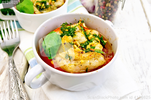 Image of Fish baked with tomato and basil in white bowl on board