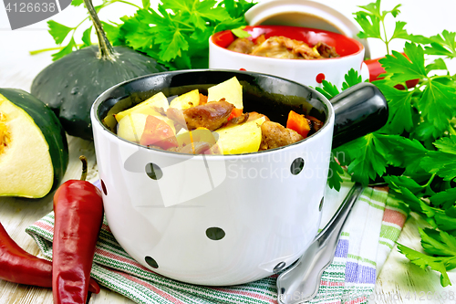 Image of Roast meat and vegetables in white pots on light board