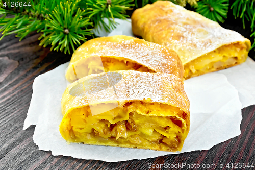 Image of Strudel pumpkin and apple with pine branches on dark board