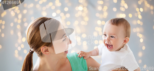 Image of happy young mother with little baby over lights