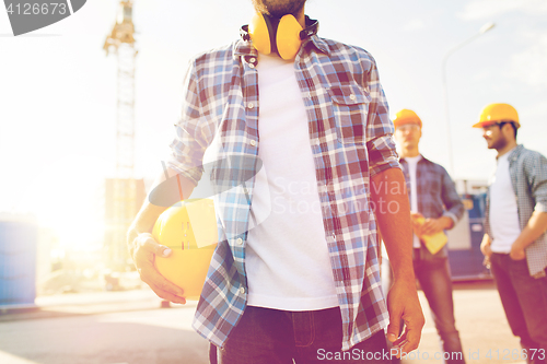 Image of close up of builder holding hardhat at building