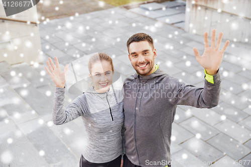 Image of couple of sportsmen waving hands outdoors in city