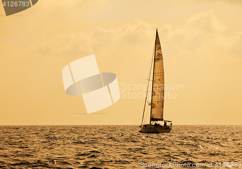 Image of Yacht sailing against sunset