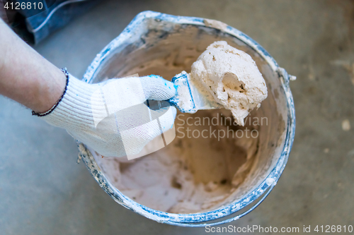 Image of Builder&#39;s hand with spatula and cement