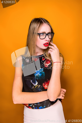 Image of The serious frustrated young beautiful business woman on orange background