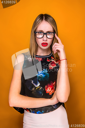 Image of The serious frustrated young beautiful business woman on orange background