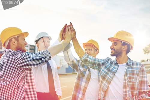 Image of close up of builders in hardhats making high five