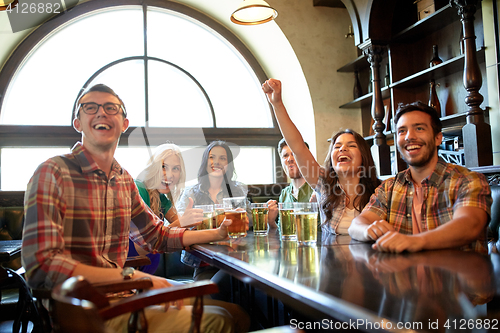 Image of friends with beer watching football at bar or pub