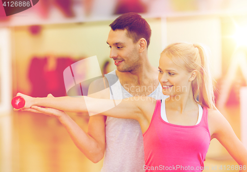 Image of male trainer with woman working out with dumbbell