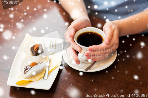 Image of close up of woman holding coffee cup and dessert