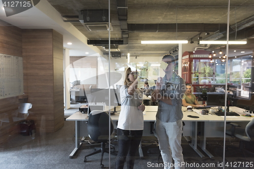 Image of young couple at modern office interior writing notes on stickers