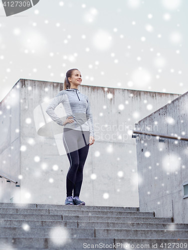 Image of smiling sportive woman on stairs at city