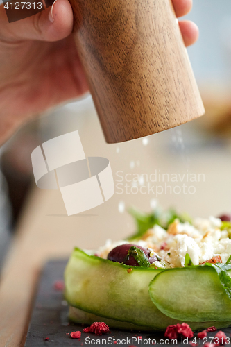 Image of close up of hand with salt shaker salting salad