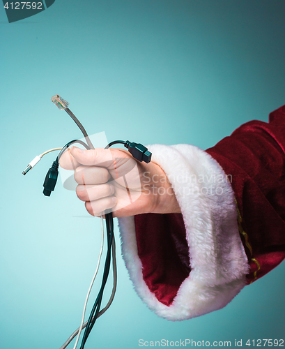 Image of Hand of Santa Claus holding a bunch connectors to gadgets on blue background