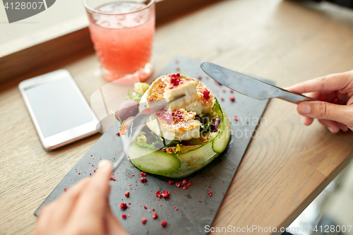 Image of woman eating goat cheese salad at restaurant