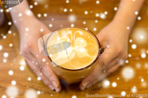 Image of close up of hands with latte art in coffee cup