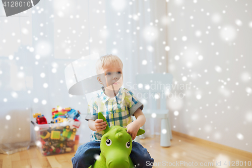 Image of happy baby boy playing with ride-on toy at home