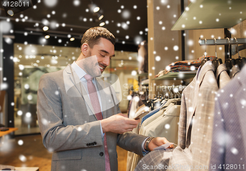 Image of man in suit with smartphone at clothing store