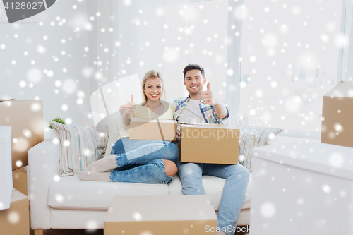 Image of happy couple with boxes showing thumbs up at home