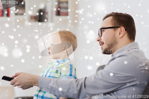 Image of father and son with remote watching tv at home