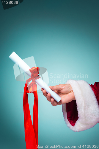 Image of Hand of Santa Claus holding a gift on blue background