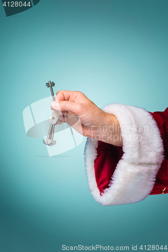 Image of Hand of Santa Claus holding the key on blue background