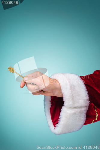 Image of Hand of Santa Claus holding the key on blue background