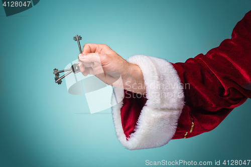 Image of Hand of Santa Claus holding the key on blue background