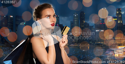 Image of woman with credit card and shopping bags in city