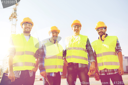 Image of group of smiling builders with tablet pc outdoors