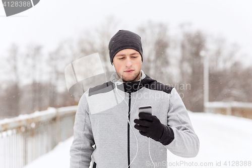 Image of happy man with earphones and smartphone in winter