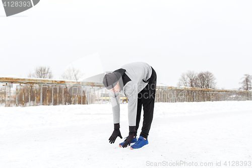 Image of man exercising and stretching leg on winter bridge