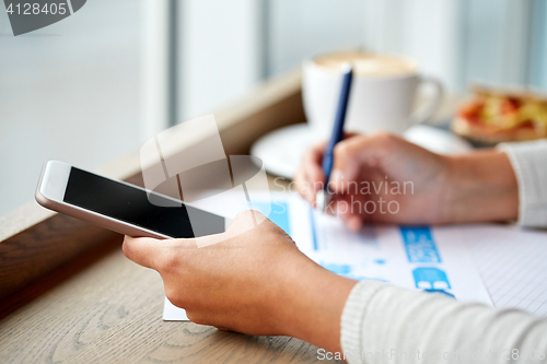 Image of woman with smartphone and chart at cafe