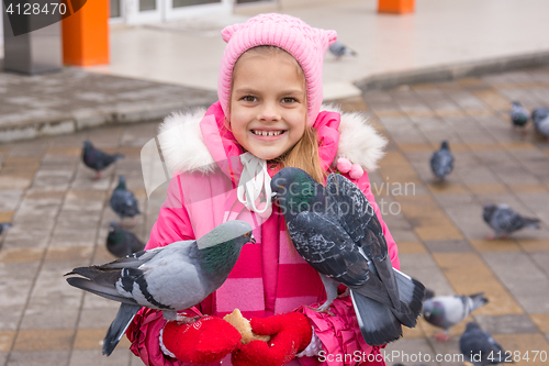 Image of Pigeons sit on a girl that feeds them