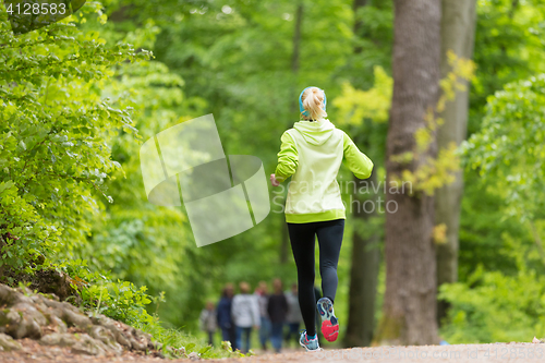 Image of Sporty young female runner in the forest. 