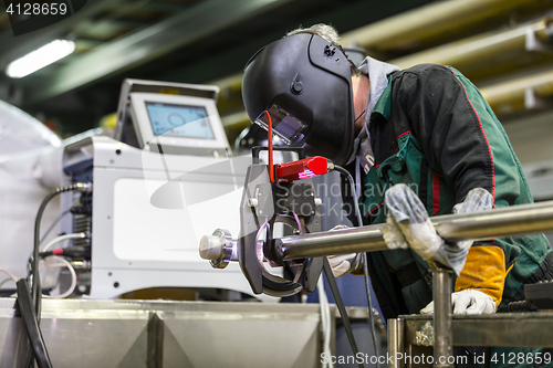 Image of Industrial worker setting orbital welding machine.